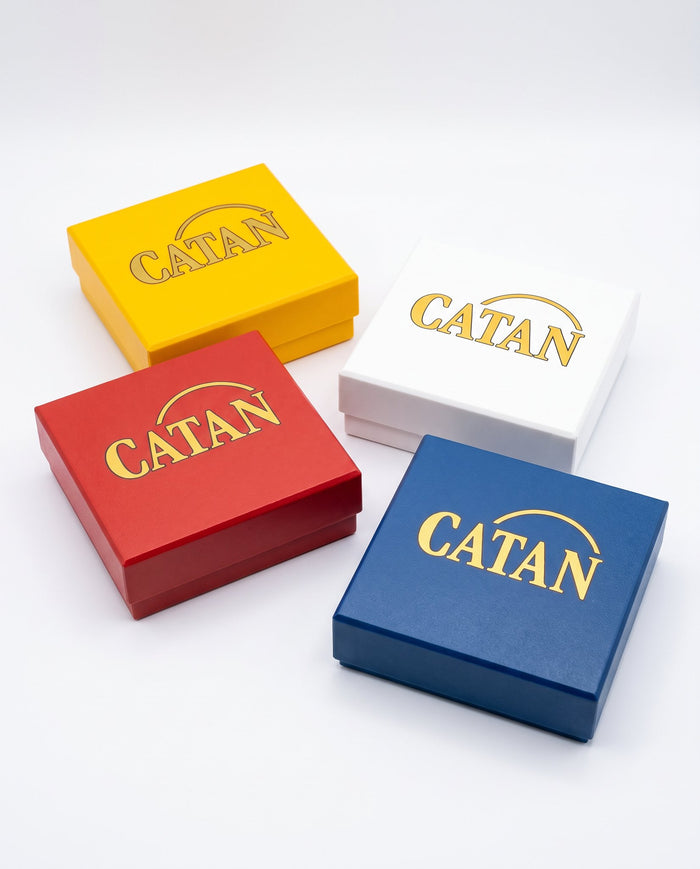Cuatro cajas de Catan en amarillo, blanco, rojo y azul